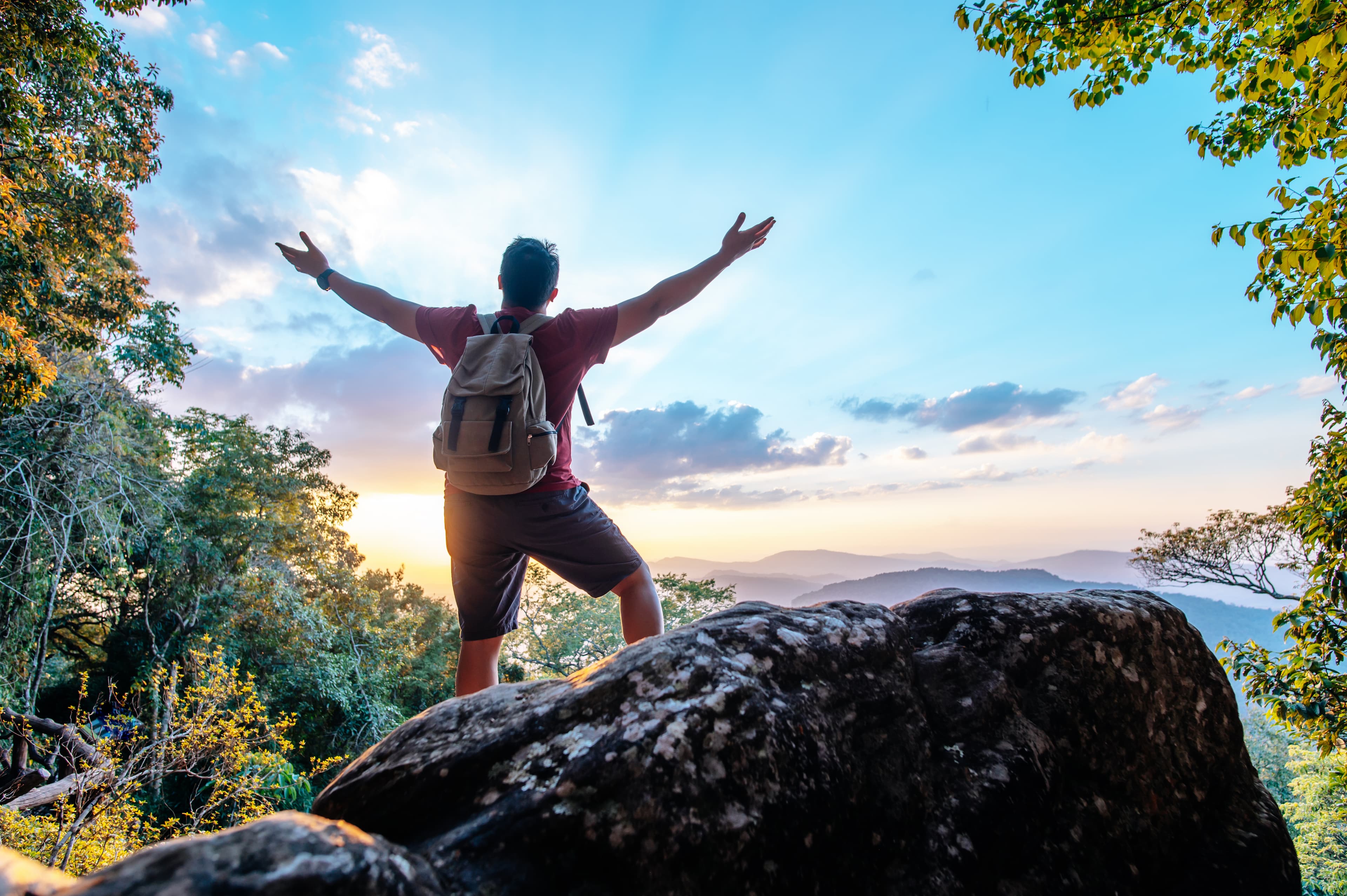 Traveller celebrating at a mountain peak
